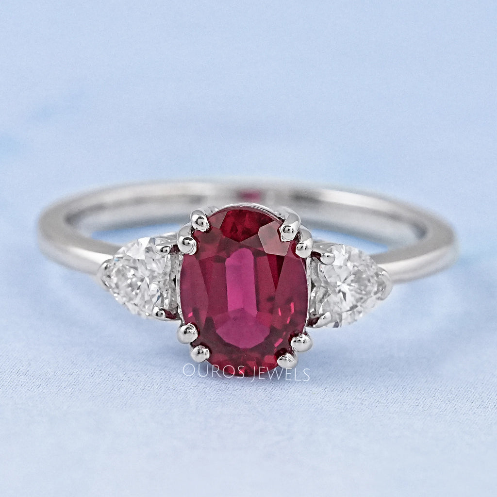 front view of oval red ruby gemstone & heart diamond three stone engagement ring