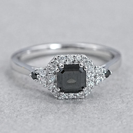 top view of asscher cut black diamond halo engagement ring on grey background