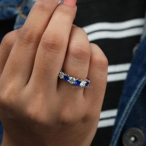 Blue Sapphire Cushion And Round Cut Diamond Eternity Wedding Band worn on a hand.