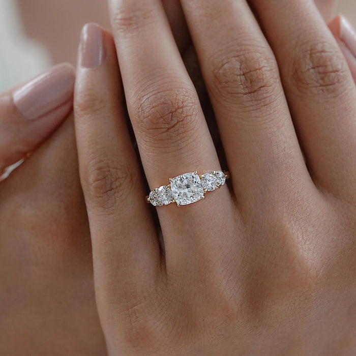 cushion cut diamond five stone engagement ring in yellow gold band on model's finger