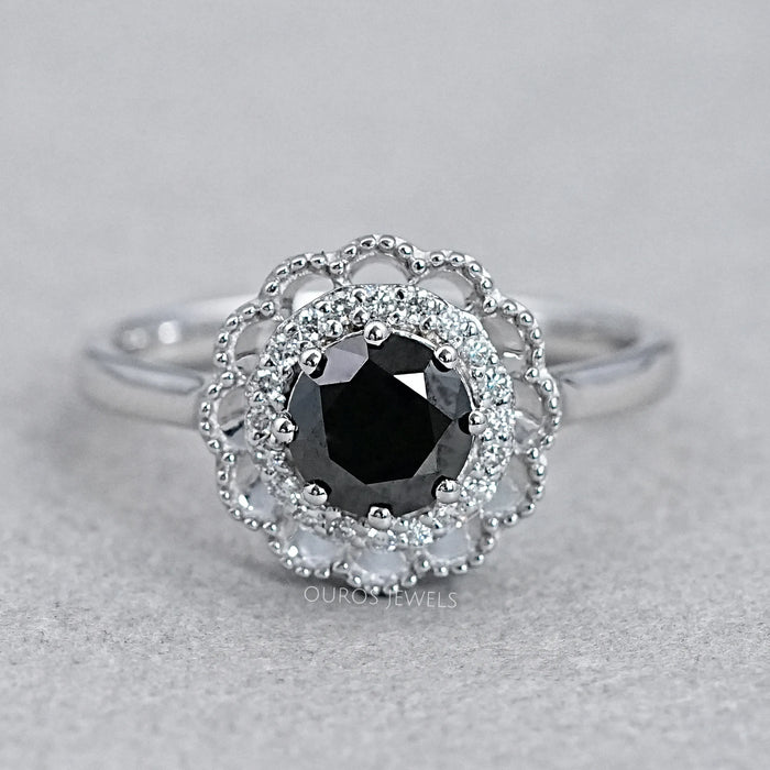 top view of round black diamond double halo engagement ring on grey fabric