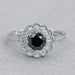 top view of round black diamond double halo engagement ring on grey fabric