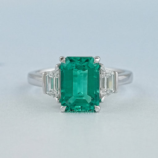 front view of green emerald gemstone with trapezoid diamond 3 stone engagement ring