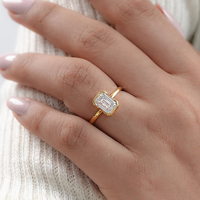 emerald cut bezel set diamond engagement ring shining on hand view