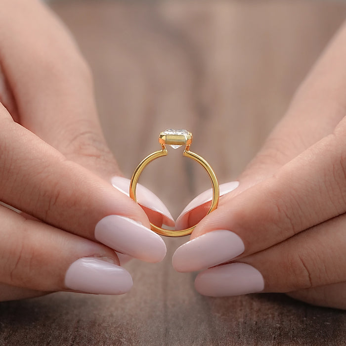 close-up view emerald cut lab diamond bezel engagement ring of women