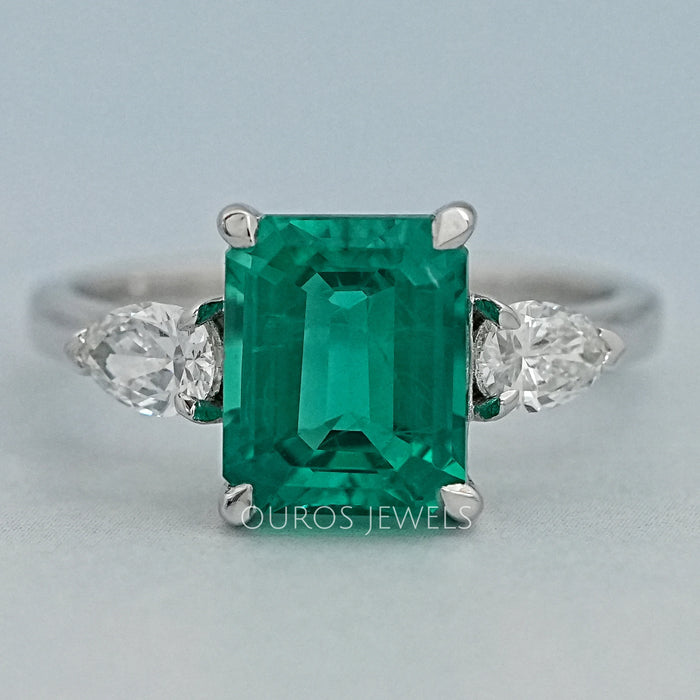 front view of green emerald gemstone pear diamond three stone engagement ring