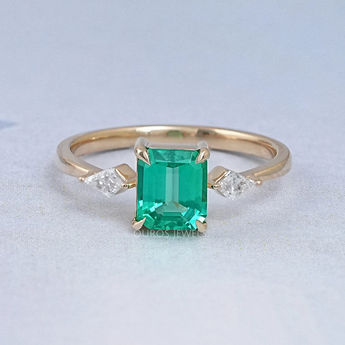 front view of green emerald gemstone and kite cut three stone engagement ring