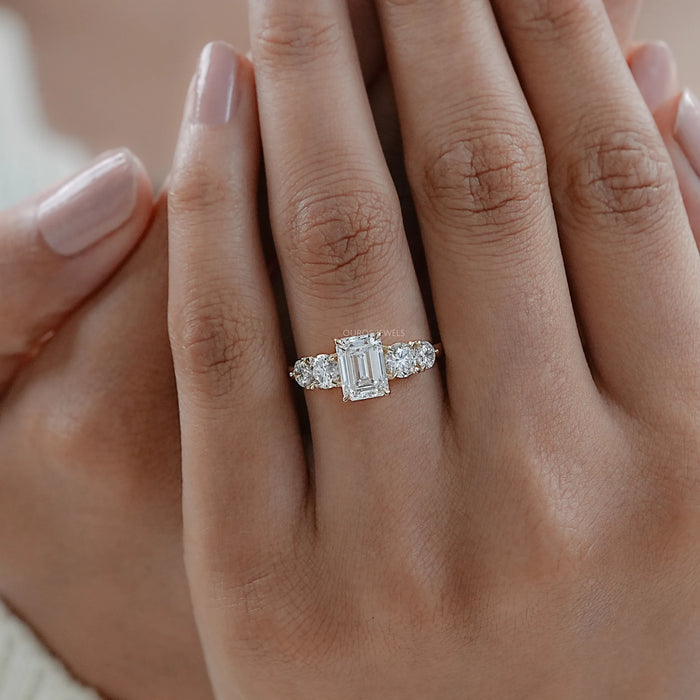 emerald cut and round lab diamond five stone engagement ring on model's finger