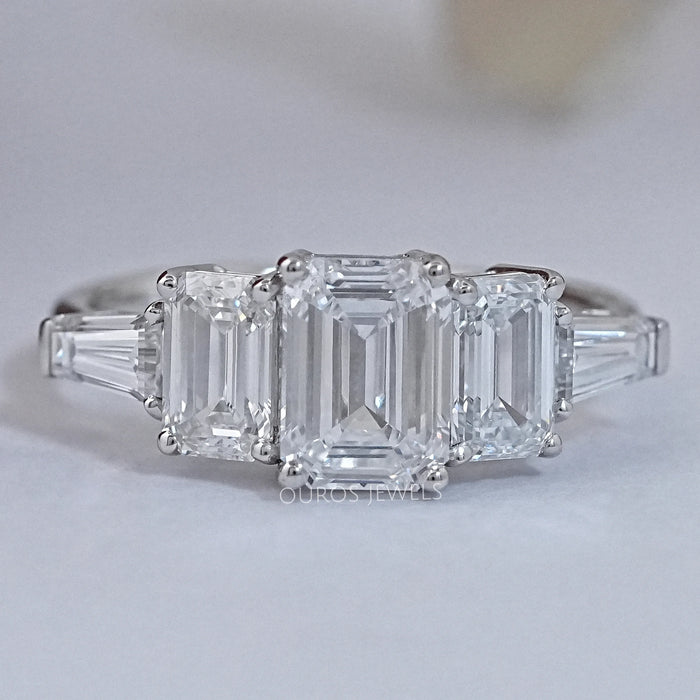 front view of emerald cut lab diamond five stone engagement ring on grey fabric