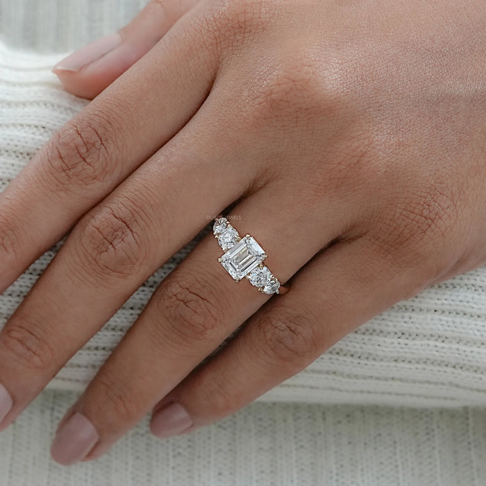 emerald cut and round lab diamond five stone engagement ring in finger