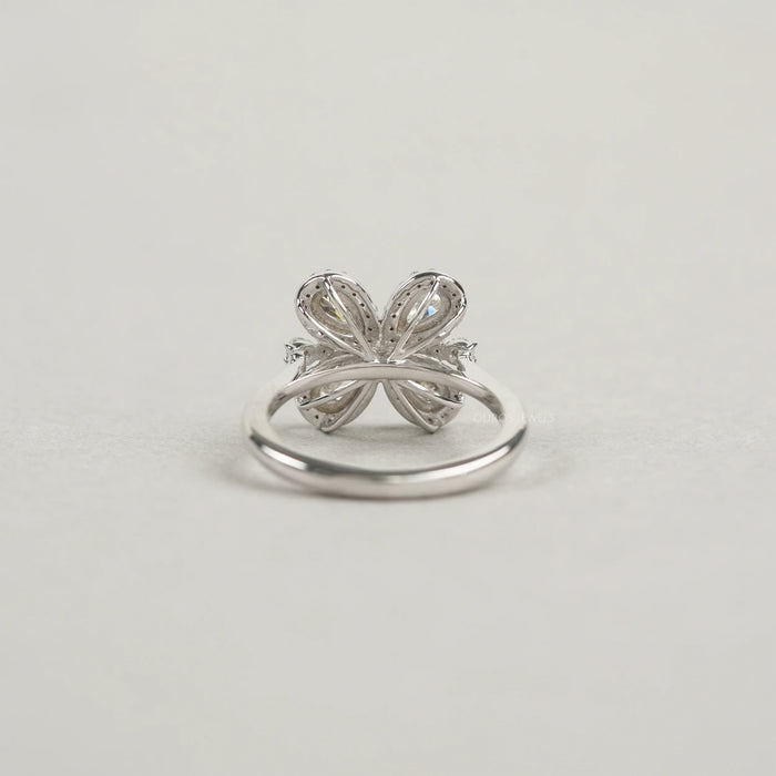 back view of olive pear cut diamond floral halo engagement ring on grey fabric