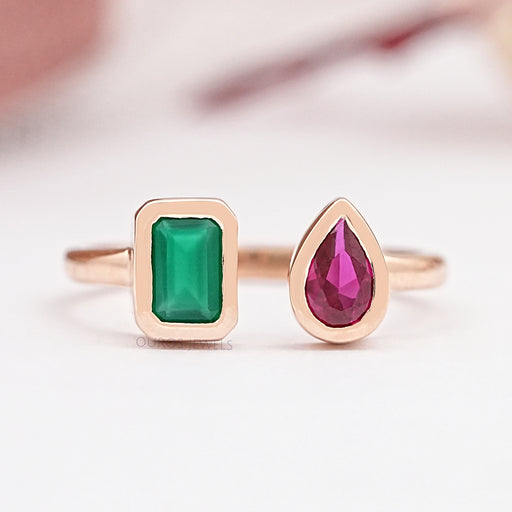 front view of rose gold bezel green emerald and red pear gemstone open wedding ring