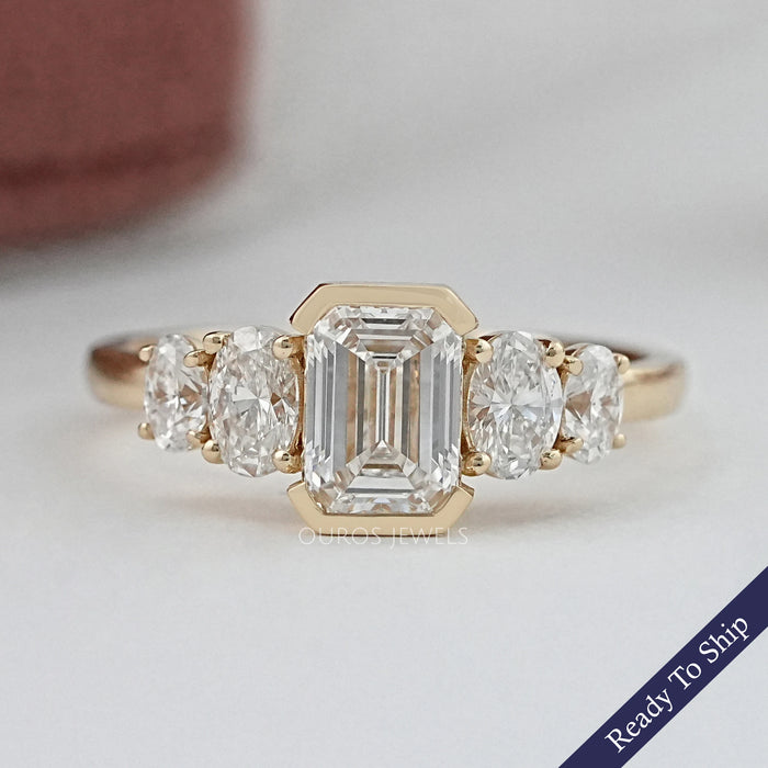 front view of emerald and oval cut diamond half bezel five stone engagement ring