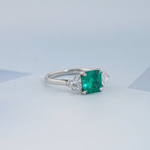 side view of green asscher gemstone with heart lab diamond 3 stone engagement ring