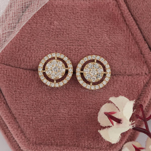 Round Brilliant Cut Diamond Halo Stud Earrings displayed on a pink velvet cushion with floral accents.