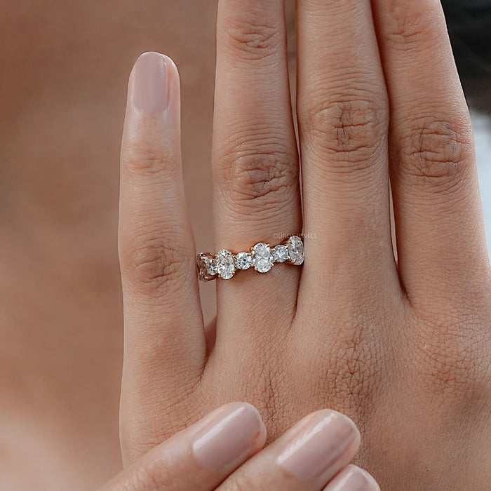 oval and round man made diamond yellow gold eternity wedding band on finger