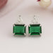 front view of emerald green gemstone and trillion cut diamond stud earrings