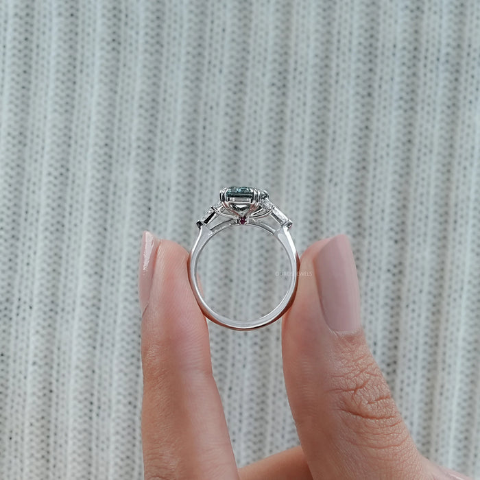 close view of green scissors cut diamond double prong three stone engagement ring