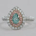 front view of green pear cut diamond double halo engagement ring on grey fabric