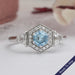 top view of blue hexagon cut diamond halo engagement ring 3 stone on grey fabric 