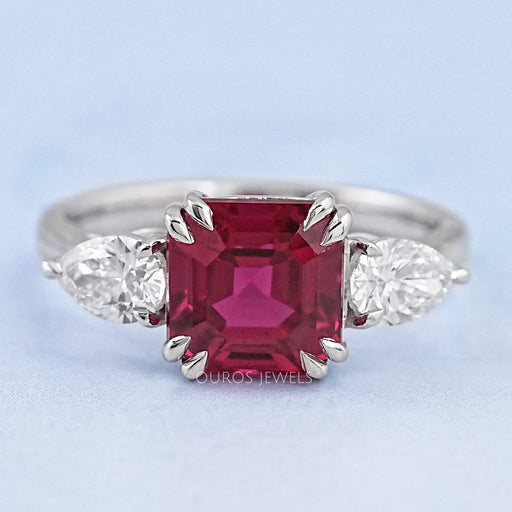 front view of asscher cut ruby and pear diamond double prong 3 stone wedding ring