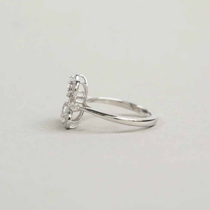 side view of olive pear cut diamond floral halo engagement ring on grey fabric