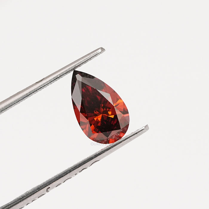 orange and red mix color pear diamond holded with tweezer