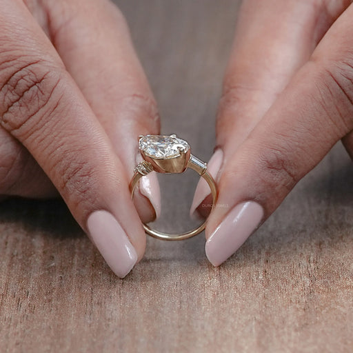 close view of pear-cut diamond solitaire accent engagement ring with yellow gold band