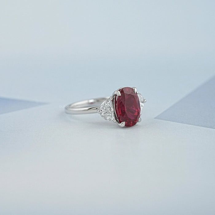 side view of oval ruby gemstone and half moon diamond 3 stone engagement ring