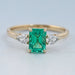 front view of green emerald gemstone and pear diamond three stone engagement ring