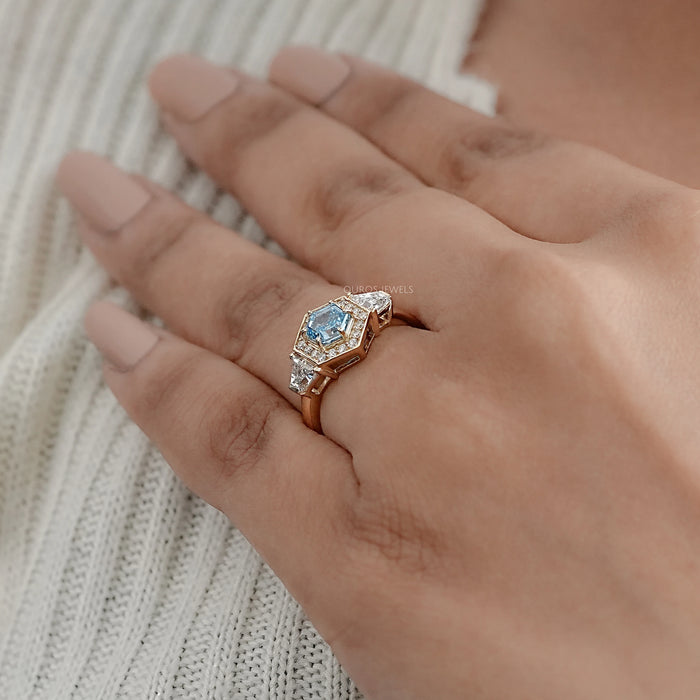 blue hexagon-cut lab diamond halo 3-stone colored engagement ring in finger