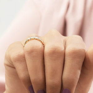 Round Cut Lab Diamond Eternity Wedding Band worn on a hand with light purple nail polish, showcasing alternating round and baguette-cut lab-created diamonds against a soft pink background.