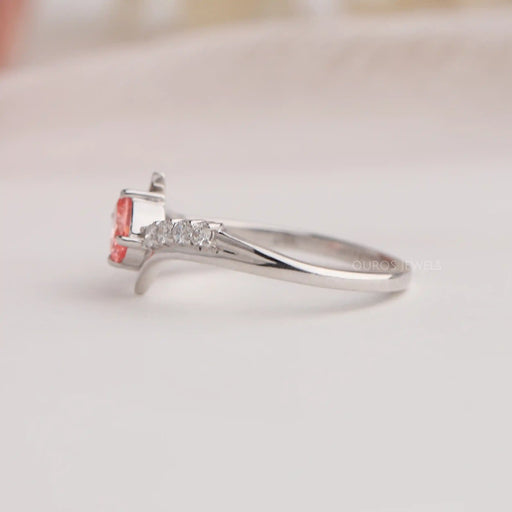 Side view of oval cut diamond engagement ring with curved band & pink color oval diamond.